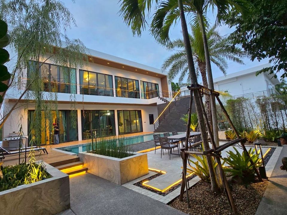 Exterior view of Sea Moment IV Pool Villa in Rayong at dusk, showcasing modern architecture and illuminated landscaping.