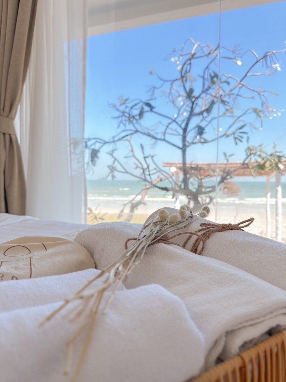 Close-up of fresh towels and dried flowers in a Story II Pool Villa Hua-Hin bedroom, with a stunning beachfront view.