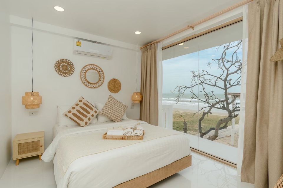 Bright bedroom with king-size bed and ocean view at Story II Pool Villa Hua-Hin. Rattan decor and natural light.