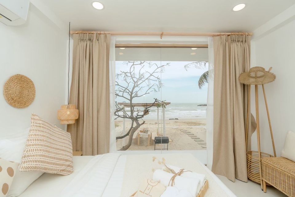 Bright bedroom at Story II Pool Villa Hua-Hin with a comfortable bed and direct beachfront views of the ocean.