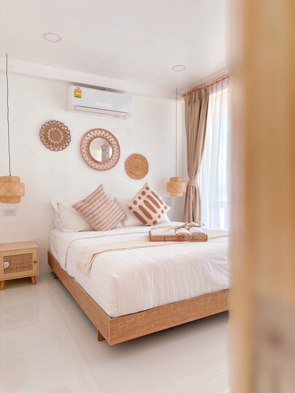 Bright bedroom at Story II Pool Villa Hua-Hin with a wooden bed frame, white linens, and boho-chic decor. Perfect for a rela
