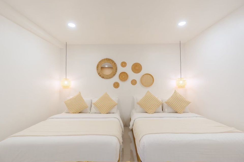 Bright bedroom with two double beds, striped pillows, and woven wall decor at Story II Pool Villa Hua-Hin.