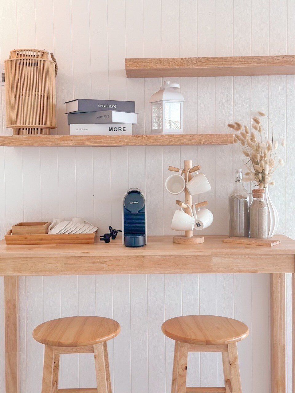 A cozy coffee bar with a Nespresso machine, wooden stools, and decorative shelves at Story II Pool Villa Hua-Hin.