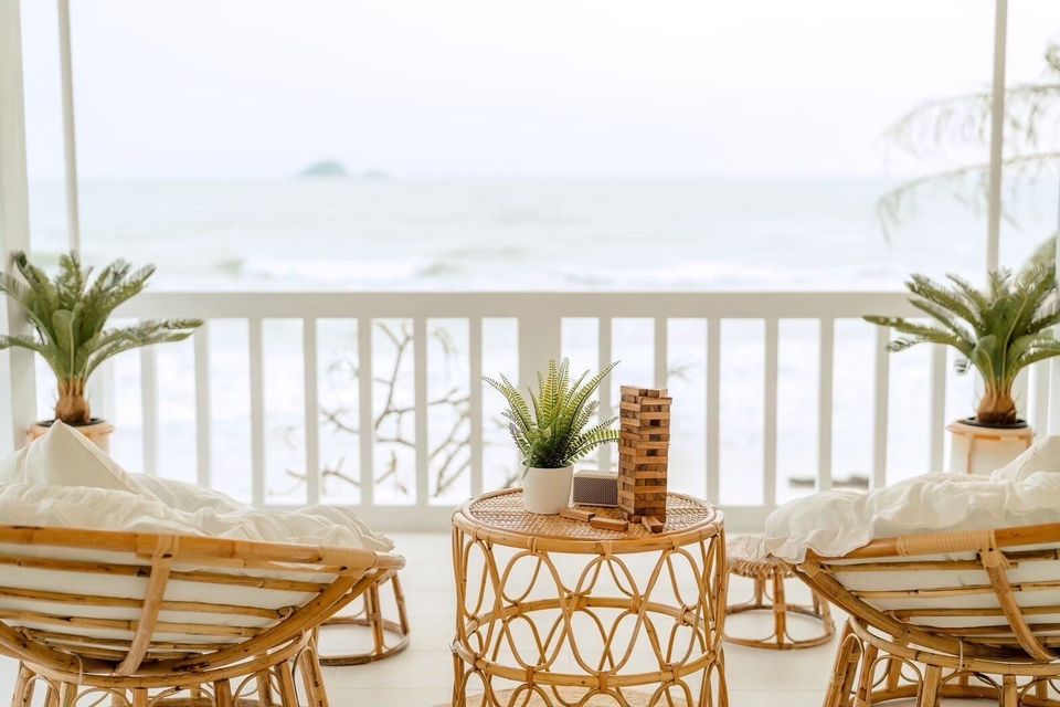 Rattan chairs and table with Jenga on a balcony overlooking the ocean at Story II Pool Villa Hua-Hin.