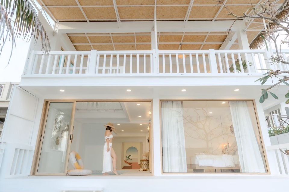 The bright white modern facade of Story II Pool Villa Hua-Hin, featuring a balcony and large sliding glass doors.