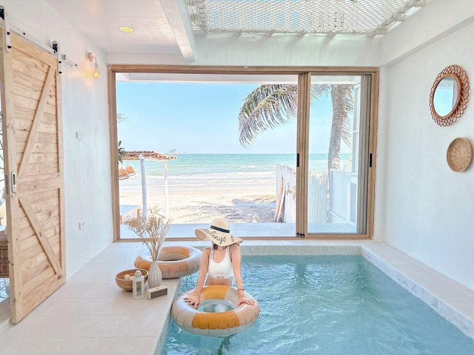 Story II Pool Villa Hua-Hin indoor pool with beach view. Woman relaxing on inflatable ring. เขาเต่า-หัวหิน pool villa.