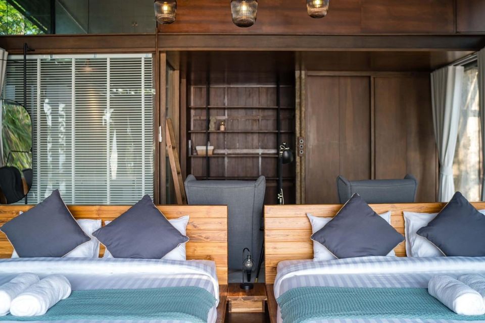 Two comfortable twin beds with wooden headboards and grey pillows in Studio Beachfront III Pool Villa, Cha-Am.