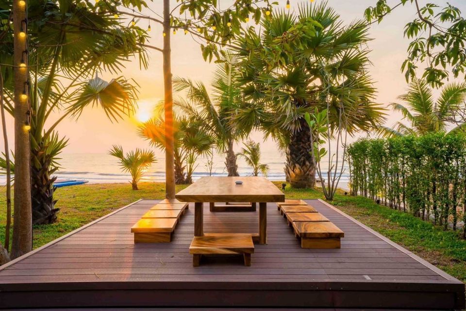 Enjoy beachfront dining at sunset on the wooden deck of Studio Beachfront III Pool Villa in Cha-Am, Thailand.