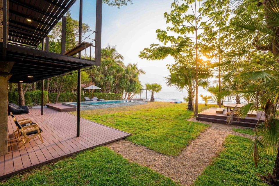 Studio Beachfront III Pool Villa in Cha-Am at sunset, showing the modern exterior, lush garden, pool, and direct beach access.