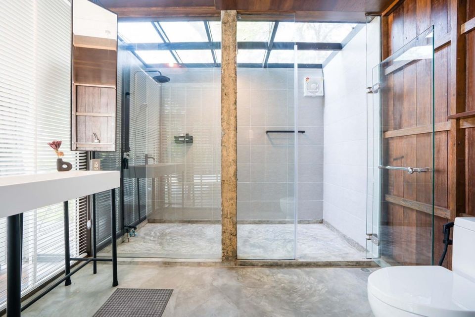 Modern bathroom with glass-enclosed rain shower and skylight at Studio Beachfront III Pool Villa, Cha-Am.