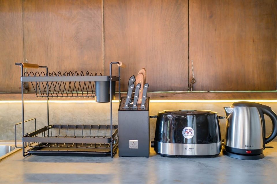 Modern kitchen appliances and utensils, including a dish rack, knife block, rice cooker, and kettle at Studio Beachfront III Pool Villa, Cha-Am.