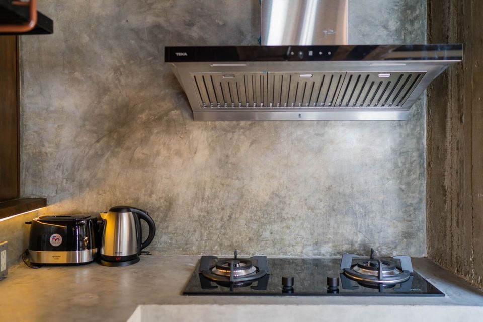 Modern kitchen with gas hob, stainless steel hood, toaster, and kettle at Studio Beachfront III Pool Villa, Cha-Am.