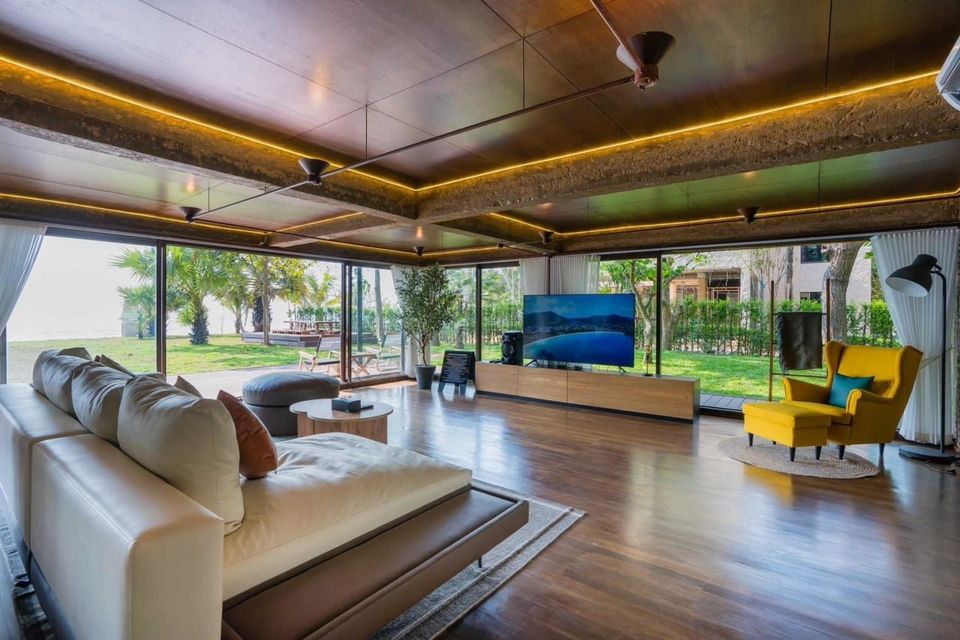 Spacious beachfront living room at Studio Beachfront III Pool Villa, Cha-Am, with large sofa, TV, and ocean views.
