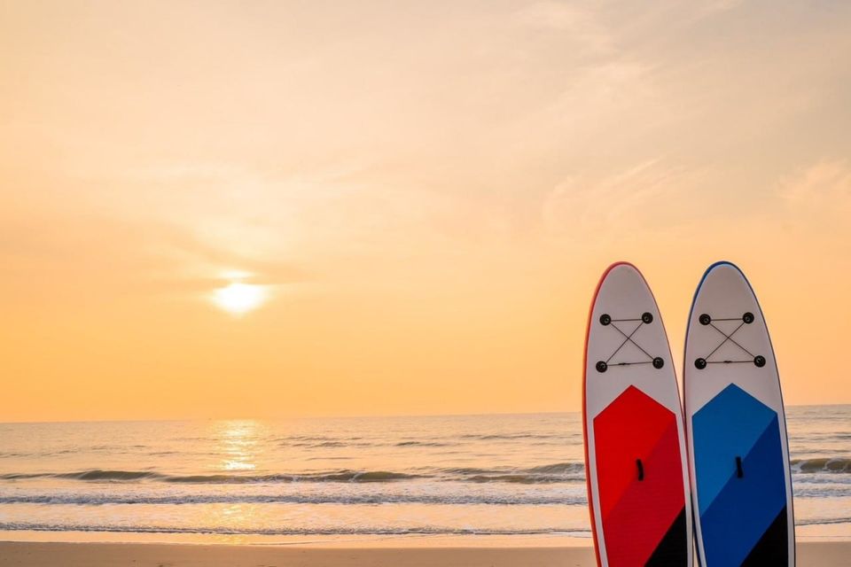 Two paddleboards on the sand at sunset, with the ocean in the background. Studio Beachfront III Pool Villa, Cha-Am.