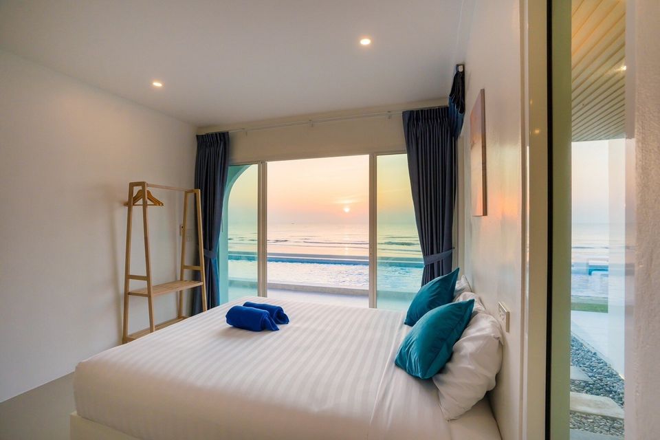 King bed beside a sunset sea-view window at Sun Sea V Pool Villa