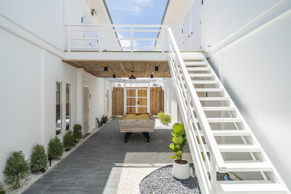 Outdoor billiards table at Talay Haus X Pool Villa in Cha-Am, with white stairs and bamboo wall accents.
