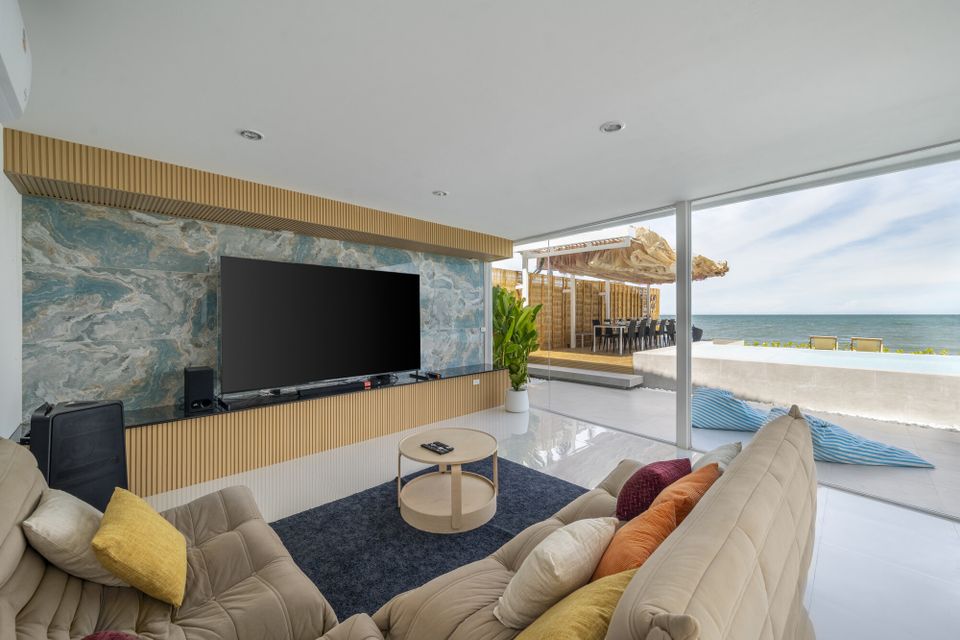 Spacious living room at Talay Haus X Pool Villa, Cha-Am, with large TV, comfortable sofas, and direct ocean views.