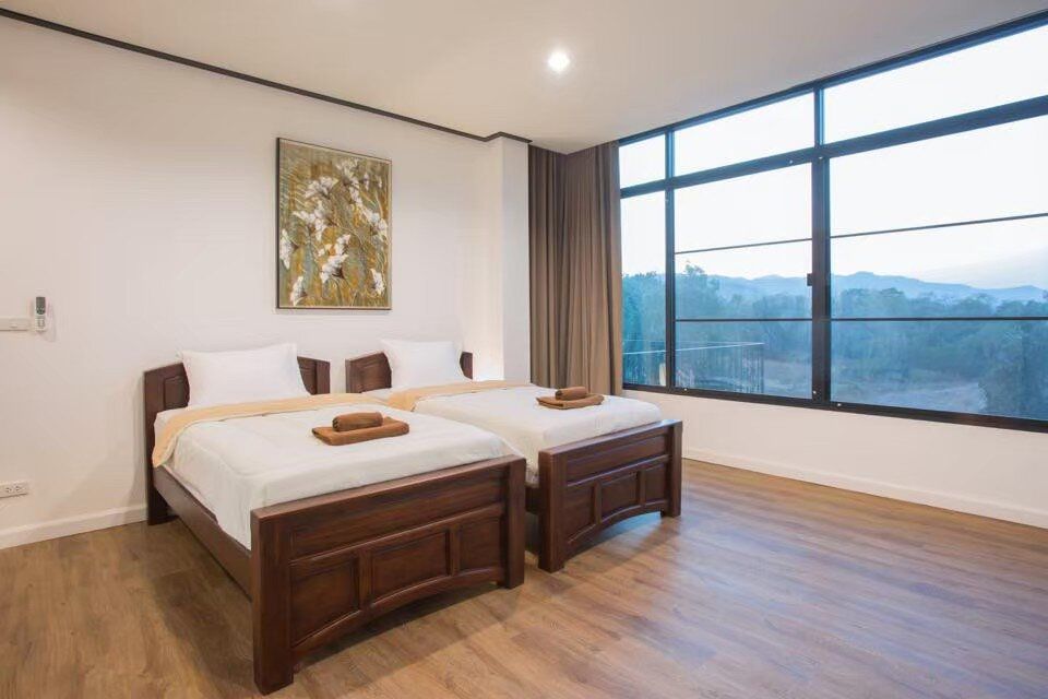 Bedroom with two twin beds and large window offering mountain views at The Valley Khaoyai V Villa, Khao Yai.