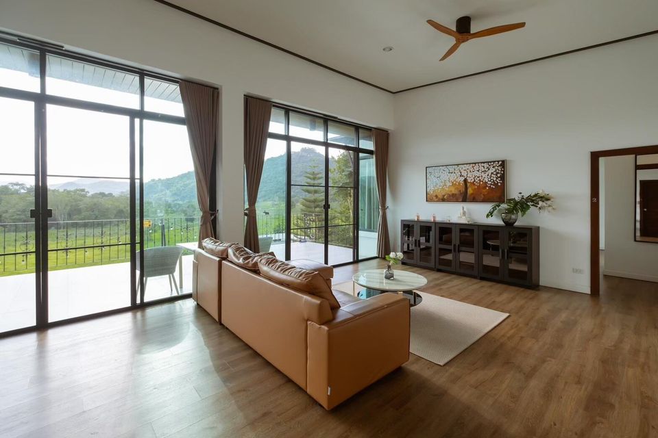 Spacious living room at The Valley Khaoyai V Villa with a comfortable brown sofa, coffee table, and stunning mountain views.