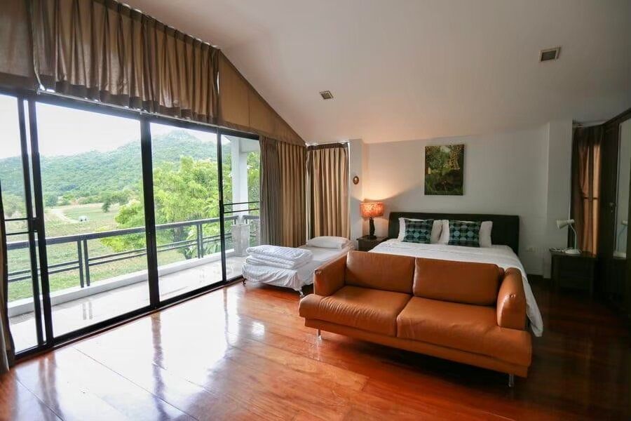 Spacious bedroom at The Valley Khaoyai I with a king-size bed, sofa, and private balcony overlooking lush mountains.