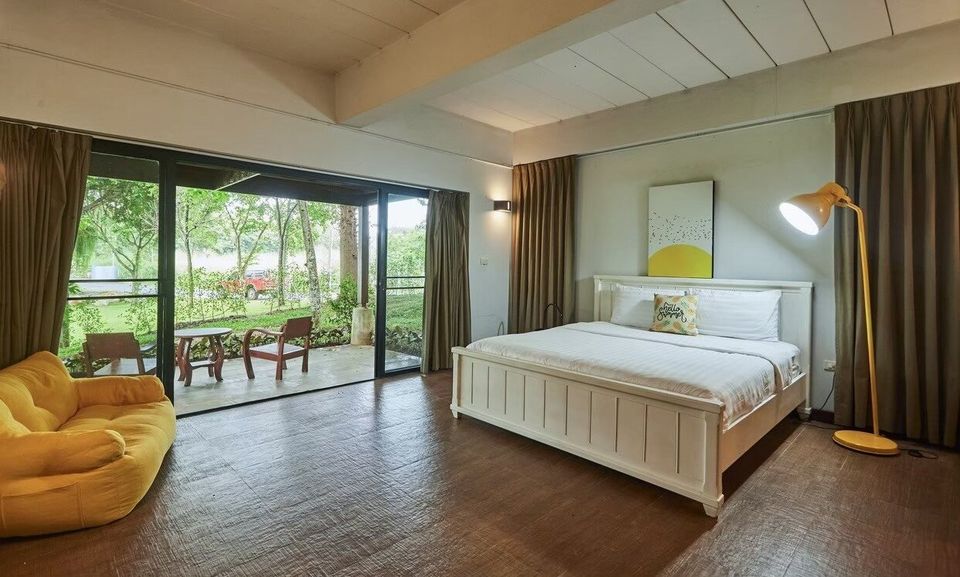 Spacious bedroom at The Valley Khaoyai I with a king-size bed, yellow bean bag sofa, and private patio access to nature.