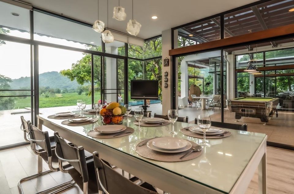 Elegant indoor dining table set for eight at The Valley Khaoyai I, offering stunning mountain views and access to a pool...