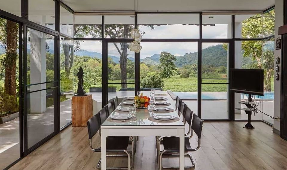 Elegant dining area at The Valley Khaoyai I, Khao Yai, with a glass table set for 10, offering stunning mountain views.