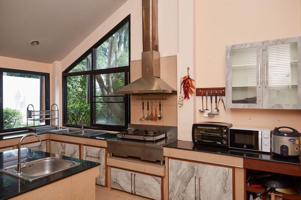 Spacious kitchen with large windows, double sink, and cooking appliances at The Valley Khaoyai I pool villa.