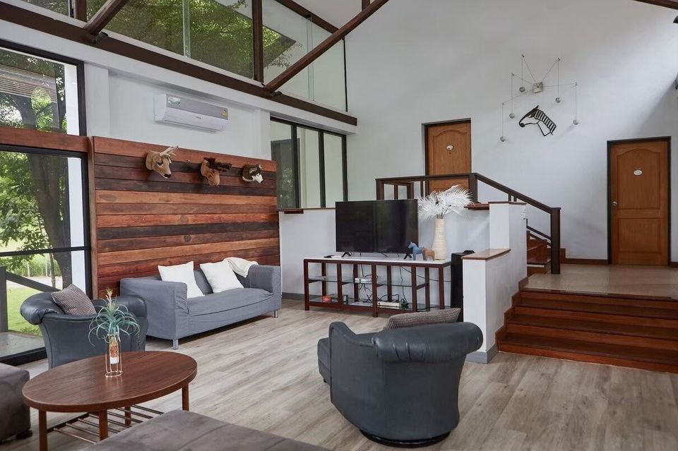 Spacious living room at The Valley Khaoyai I, Khao Yai, featuring comfortable sofas, a large TV, and unique wall decor.