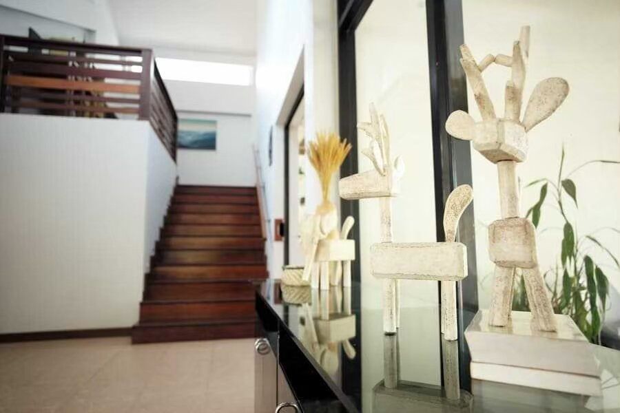 Interior view of The Valley Khaoyai I villa, showing a wooden staircase and decorative deer sculptures on a console table.