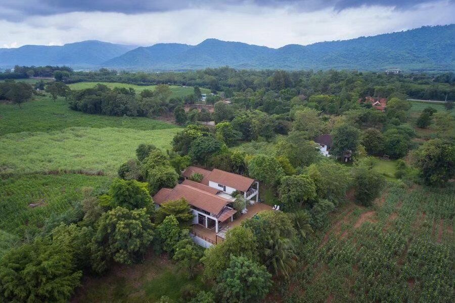 Aerial view of The Valley Khaoyai I pool villa, nestled among lush trees with mountains in the background, Khao Yai.