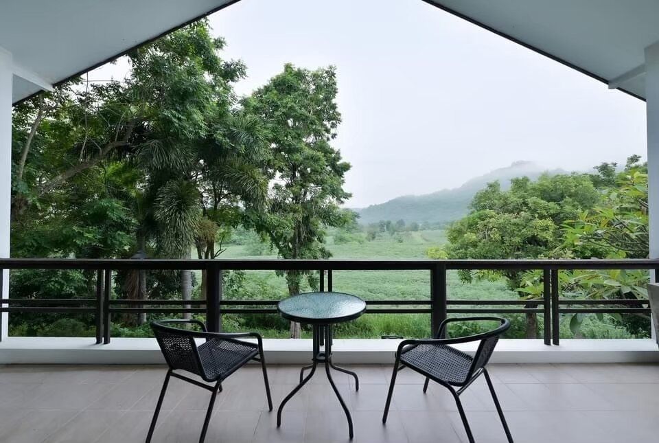 Balcony with two chairs and a table at The Valley Khaoyai I, offering lush green mountain views in Khao Yai.