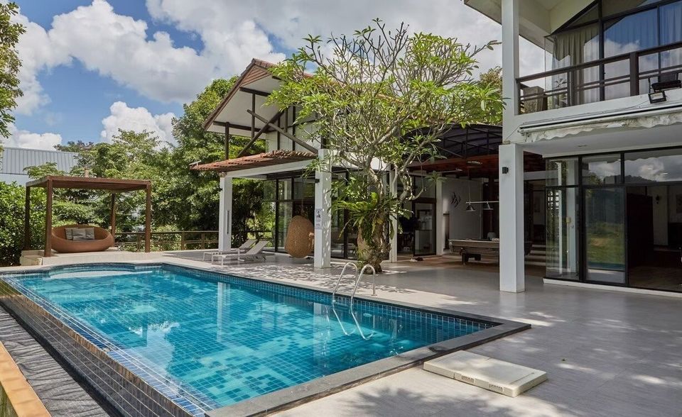 The Valley Khaoyai I pool villa in Khao Yai features a large outdoor swimming pool, sun loungers, and a shaded daybed.
