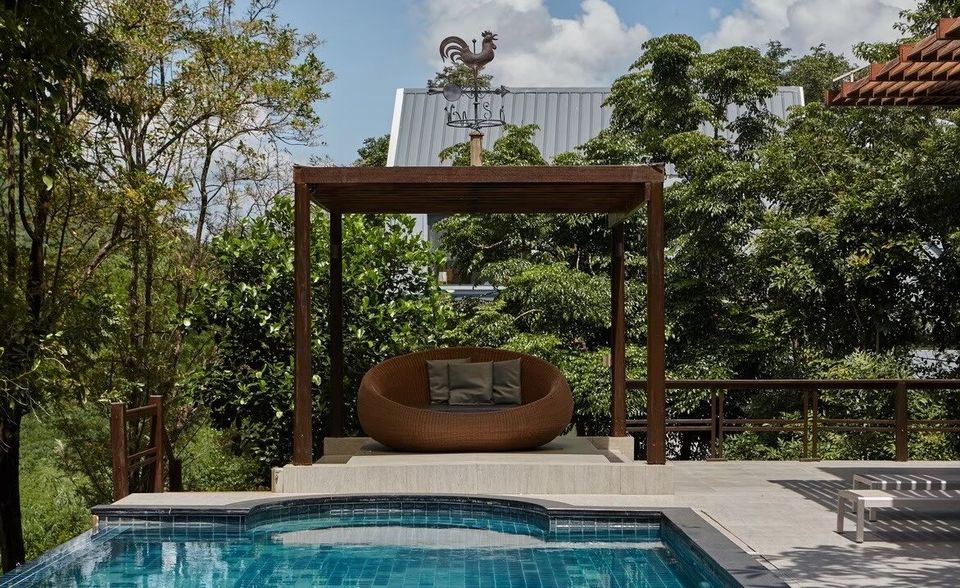 The Valley Khaoyai I pool villa features a refreshing blue tiled pool and a shaded daybed with a weathervane.