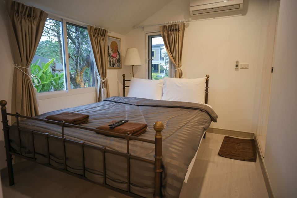 A cozy double bed with grey bedding and white pillows in a bedroom at The Valley Khaoyai IX Villa, Khao Yai.