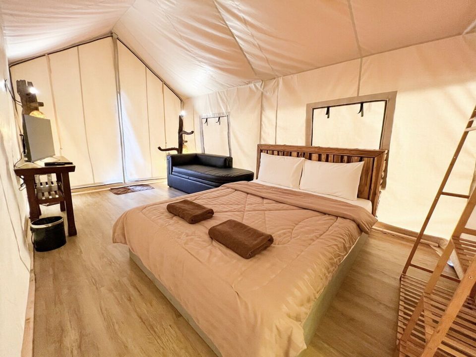 Cozy glamping tent bedroom at The Valley Khaoyai IX Villa, Khao Yai, featuring a comfortable bed, sofa, and TV area.