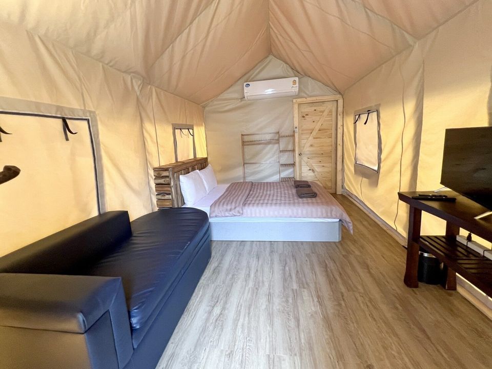 Cozy glamping tent bedroom at The Valley Khaoyai IX Villa, Khao Yai, featuring a comfortable bed, sofa, and TV.