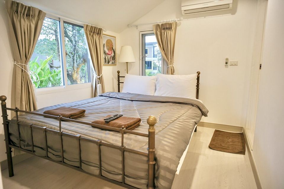 Comfortable king-size bed with grey bedding and brown towels in a bedroom at The Valley Khaoyai IX Villa, Khao Yai.