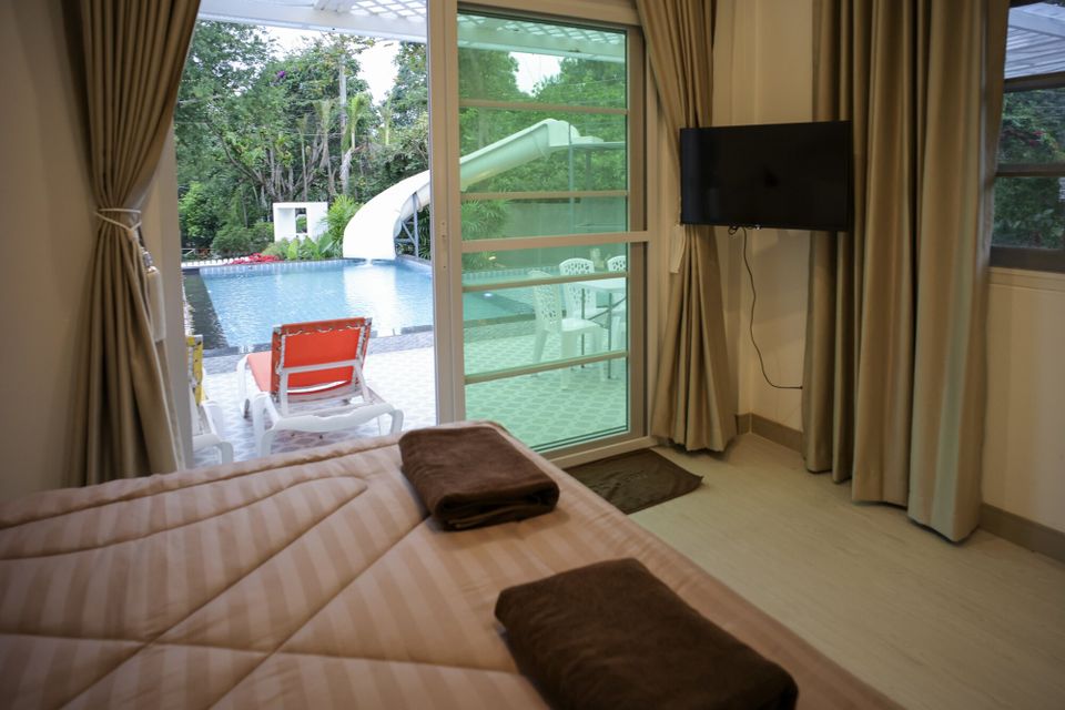 Bedroom with a comfortable bed and a view of the pool and water slide at The Valley Khaoyai IX Villa, Khao Yai.