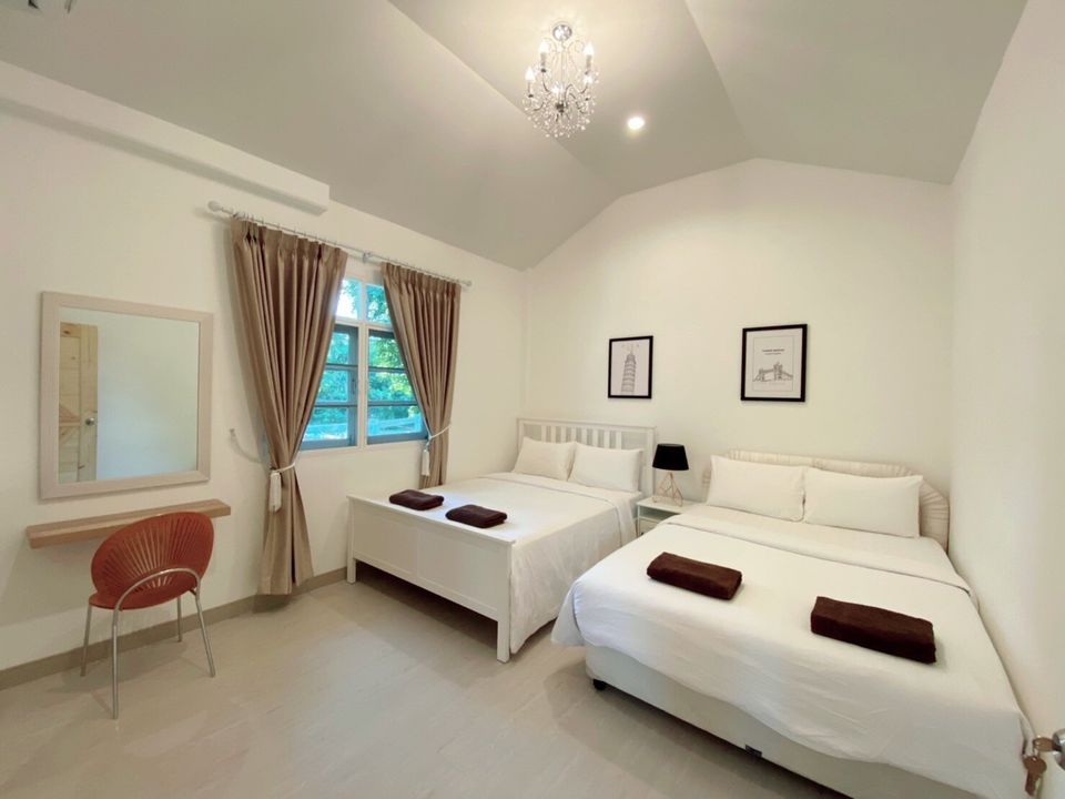 Bright bedroom at The Valley Khaoyai IX Villa with two queen-sized beds, white linens, and a vanity mirror. Ideal for families.