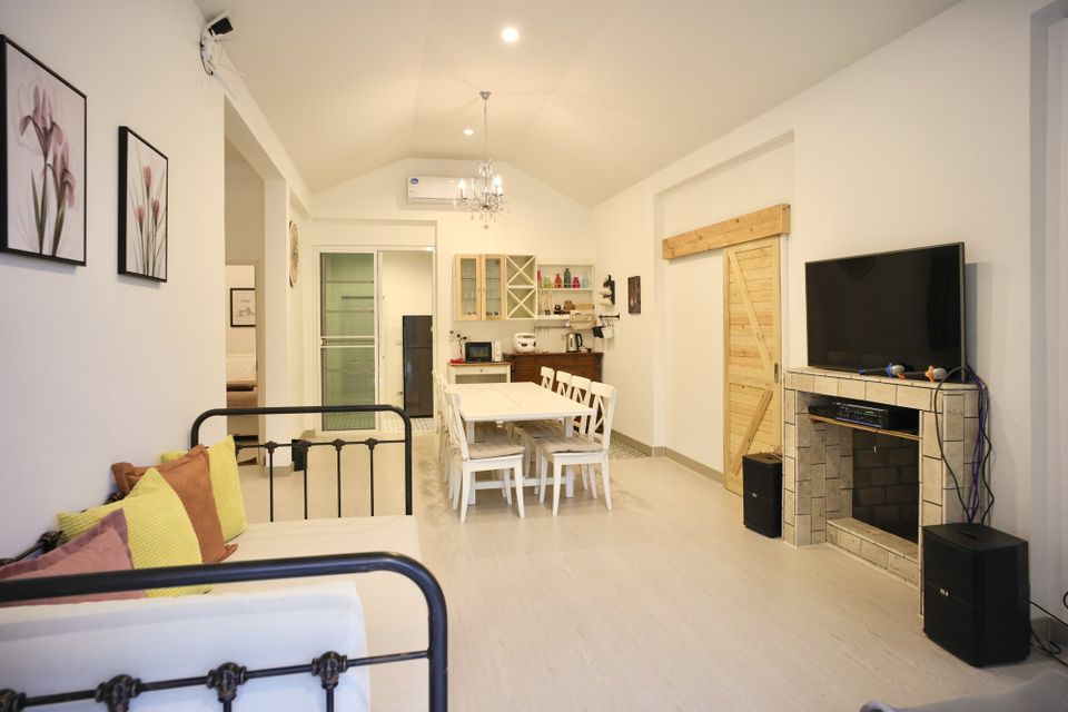 Spacious living area with a large TV, karaoke setup, and dining table at The Valley Khaoyai IX Villa, Khao Yai.