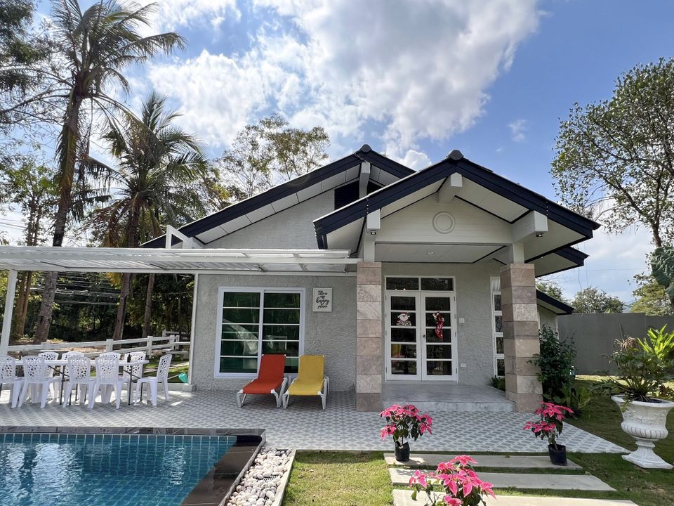 The Valley Khaoyai IX Villa exterior on a sunny day, showing the pool, outdoor dining, and lush greenery in Khao Yai.