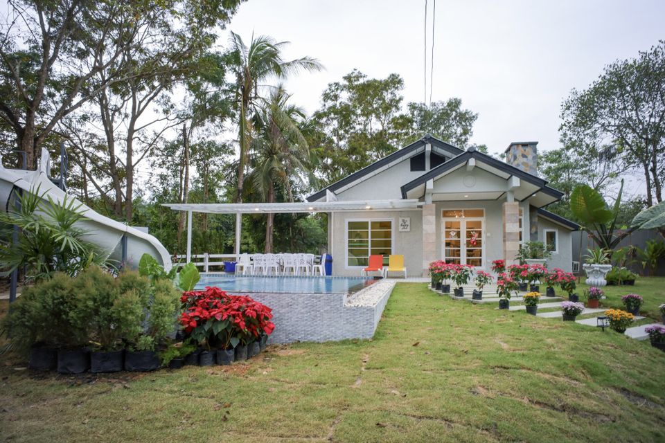 The Valley Khaoyai IX Villa's charming exterior with a private pool, water slide, and lush garden in Khao Yai, Thailand.