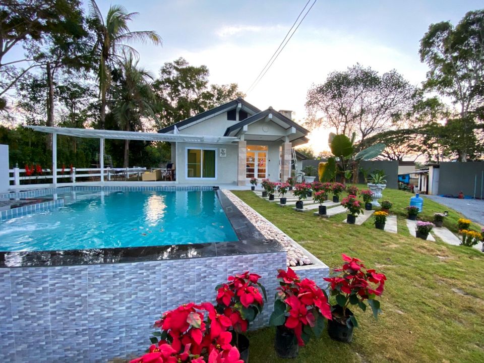 The Valley Khaoyai IX Villa exterior with private pool, lush green garden, and tropical plants under a clear sky in Khao Yai.