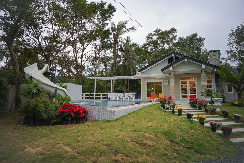 The Valley Khaoyai IX Villa exterior with a white water slide, pool, and lush green garden in Khao Yai.