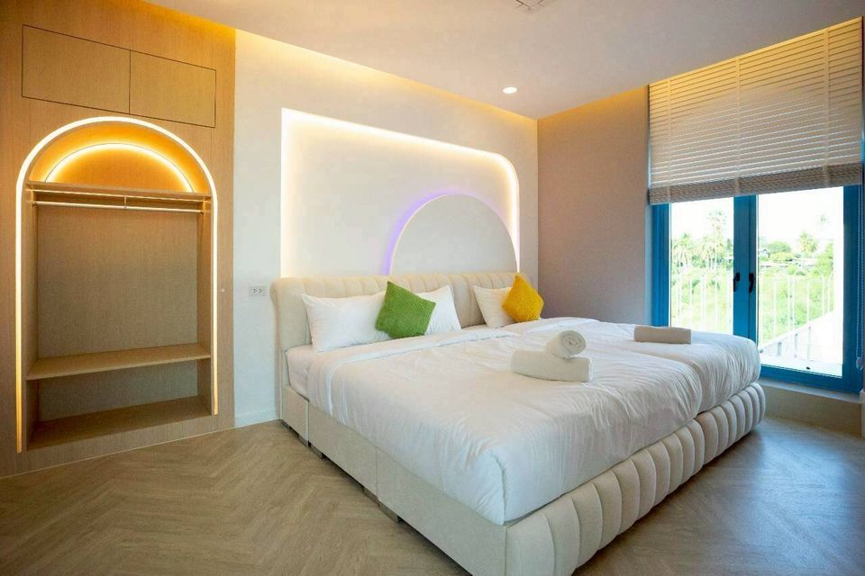 Bright bedroom at Tierra V Pool Villa, Pattaya, featuring two comfortable twin beds, a built-in wardrobe, and large windows.