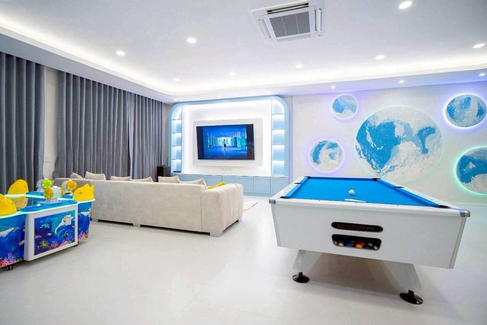 Tierra V Pool Villa in Pattaya features a bright entertainment room with a pool table, large TV, and comfortable sofas.
