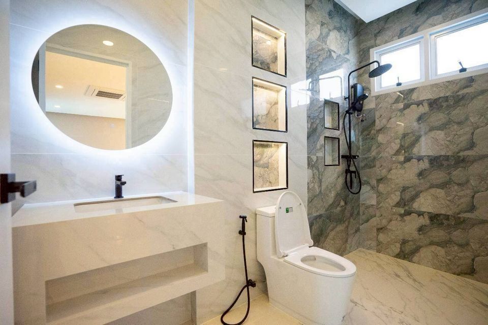 Modern bathroom at Tierra V Pool Villa, Pattaya, featuring a sleek vanity with an illuminated mirror and a spacious shower area.