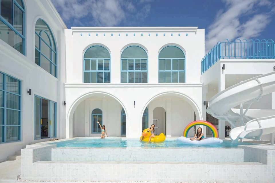 Guests enjoying the pool with a water slide and inflatables at Tierra V Pool Villa, Pattaya. Perfect for family fun.