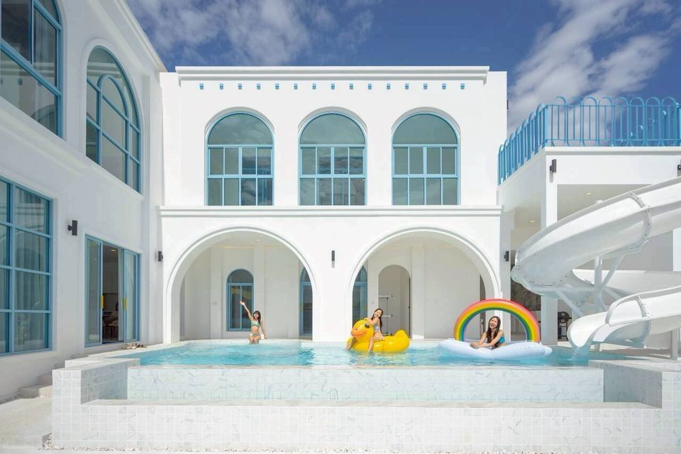 Guests enjoy the large swimming pool with a water slide at Tierra V Pool Villa in Pattaya, Thailand.